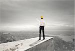 Businessman with helmet indicates the right direction on the roof above the city