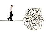 Problem and difficulty concept with a businessman who walk on a tangled rope