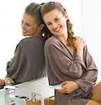 Smiling young woman with toothbrush sitting in bathroom