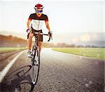 Front view of a road cyclist in uniform during a race at sunset