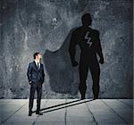 Businessman with his shadow of big super hero on the wall. Concept of powerful man