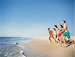 Group of friends run to the blue sea. Concept of summertime