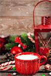 Christmas time red cup of milk and latern with candle light, holiday decorations around, copy space