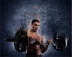 Athletic muscular man training biceps in a grunge gym