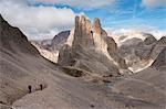 Hikers walking leaving behind Torri del Vajolet and Re Alberto refuge, Dolomites Rosengarten (Catinaccio) group, Trentino Alto Adige, Italy, Europe