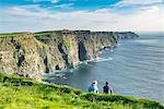 Couple admiring the landscape. Cliffs of Moher, Liscannor, Co. Clare, Munster province, Ireland.