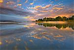 Po river park, Piedmont, Italy. Reflection on Po river banks, with clouds coloured by the sunset lights.