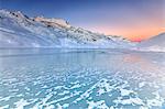 Surface of Lake Bianco of Bernina enhanced by soft colors of dawn. Canton of Graubunden. Engadine. Switzerland. Europe