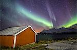 Northern Lights illuminates the wooden cabin at Svensby Lyngen Alps Tromsø Lapland Norway Europe