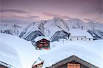 Pink sky at sunset frames the snowy mountain huts and church Bettmeralp district of Raron canton of Valais Switzerland Europe