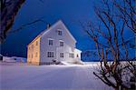 Lights on the typical wooden house surrounded by snow Flakstad Lofoten Islands Northern Norway Europe