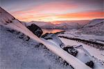 The frozen sea surrounded by snow framed by orange clouds at sunset Torsken Senja Troms County Norway Europe