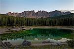 Latemar mountain range and woods are reflected in Lake Carezza at dusk Ega Valley Province of Bolzano South Tyrol Italy Europe