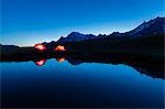 Camping tents reflected in the alpine lake at night Mont De La Saxe Courmayeur Aosta Valley Italy Europe