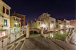 Night view of the typical gondolas moored in the canal surrounded by old buildings and bridges Venice Veneto Italy Europe