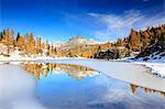 Rocky peaks and larches reflected in the frozen Lake Mufulè Malenco Valley Lombardy province of Sondrio Valtellina Italy Europe