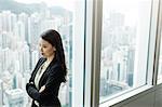 Businesswoman, arms crossed, looking out of window