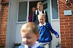 School boy and sisters leaving front door