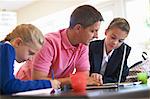 Father helping daughters with homework at kitchen counter