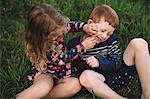 Boy and sister play fighting in field