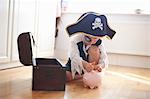 Young boy dressed as pirate, putting money into piggy bank