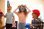 Family playing dress up, wearing funny hats and glasses, laughing