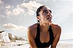 Exhausted young female runner taking a break on beach