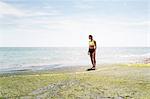 Young woman standing beside sea, looking at view