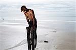 Young man training, doing push ups on wooden beach posts