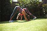 Mother and daughter exercising in garden, in yoga position