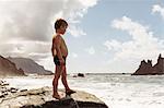 Young boy standing on rock, looking at view, Santa Cruz de Tenerife, Canary Islands, Spain, Europe
