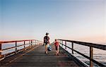 Rear view of father and son walking on pier, Goleta, California, United States, North America