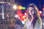 Portrait of young woman, outdoors at night, holding lip sparklers