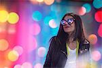 Portrait of young woman, outdoors at night, lights reflected in glasses