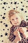 Portrait of female toddler lying on star pattern bed holding her bare feet