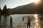 Three teenage boys standing in lake, rear view