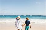 Mother and son, holding hands,standing on beach, looking at view, rear view