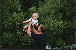 Mature man lifting up toddler son