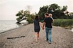 Rear view of couple strolling along beach with male toddler son, Lake Ontario, Canada