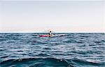 Young male sea kayaker looking at smartphone while fishing, Santa Cruz Island, California, USA