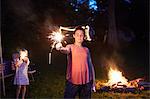 Two girls standing near camp fire, using sparklers