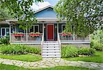 Country cottage style residential home facade with veranda in summer