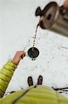 Personal perspective view of male hiker pouring coffee from flask in snow