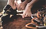 Close up of a free climber putting on rock climbing shoes with a pile of carabiners and rope.