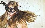 Young woman wearing a black eye mask at a party with confetti falling.