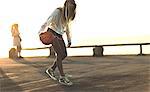 Young woman standing in front of a sunset bouncing a basketball.