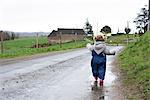 Little girl walking along wet dirt road