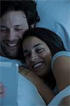 Couple using digital tablet in bed