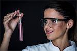 Young woman looking at liquid in test tube
