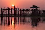 Amarapura, Mandalay region, Myanmar. Silhouetted people walking on the U Bein bridge at sunset.